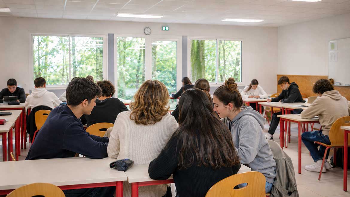 Une adulte de la vie scolaire accompagne un groupe d’élèves dans une salle de classe au lycée Saint-Joseph L’Amandier.